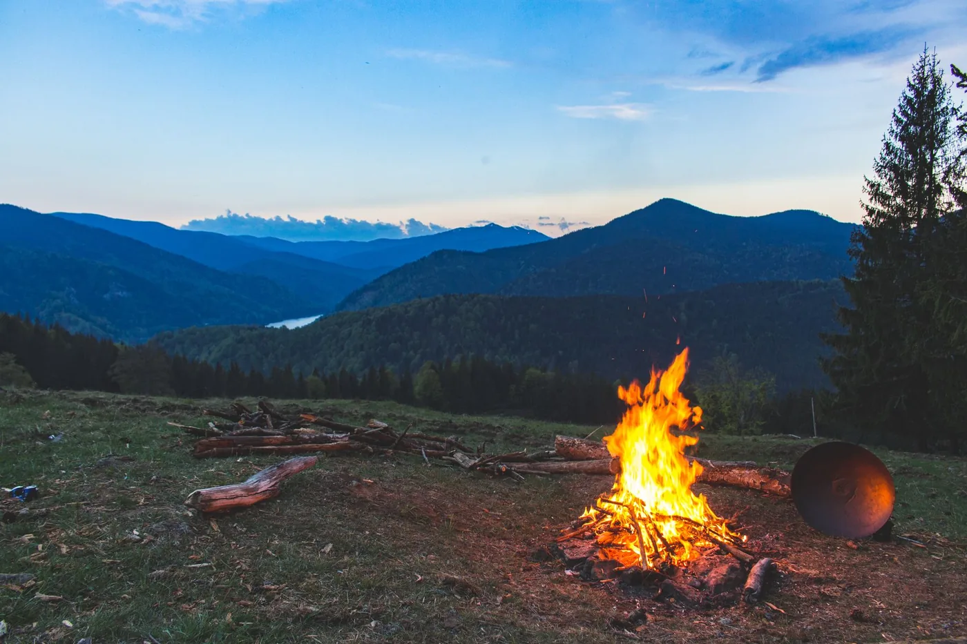 A small campfire in an open mountain landscape at dusk.