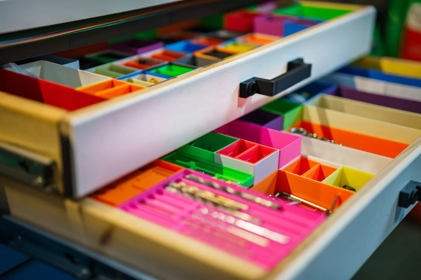 Open drawers fitted with colorful compartments for organizing small tools and parts.